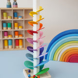 A satisfying Mini Marble Tree Ball run from Magic Wood - a tall wooden stem with rainbow leaves and wooden marbles - in the Babipur playroom next to a Gwawr rainbow and peg dolls.