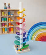 A satisfying Mini Marble Tree Ball run from Magic Wood - a tall wooden stem with rainbow leaves and wooden marbles - in the Babipur playroom next to a Gwawr rainbow and peg dolls.