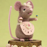 The Makerss Candy Mouse holding a cupcake and a lollypop, and wearing a pink apron on a green background