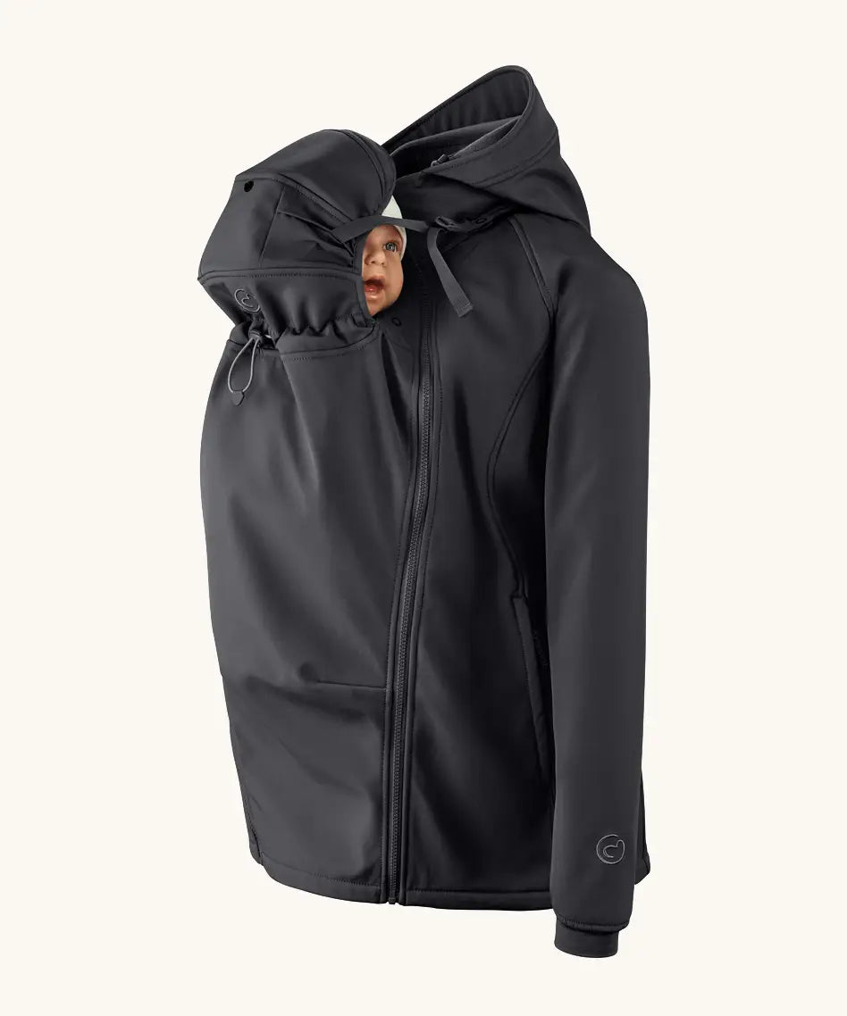 Mamalila soft shell baby wearing allrounder fitted jacket in black showing a baby doll with the protective hood covering the head