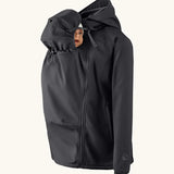 Mamalila soft shell baby wearing allrounder fitted jacket in black showing a baby doll with the protective hood covering the head
