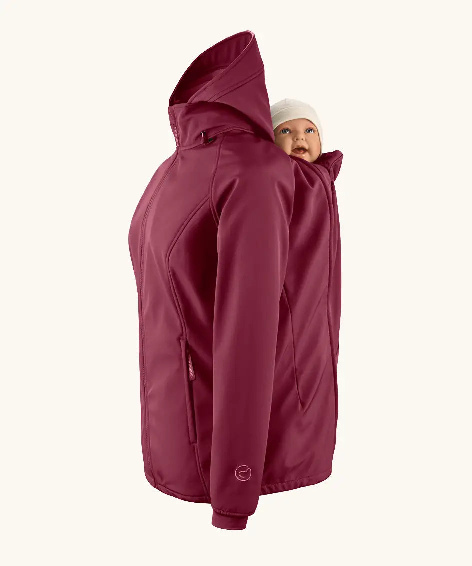 Mamalila soft shell baby wearing allrounder fitted jacket in burgundy showing a baby doll sitting on the back with the protective hood down