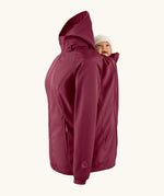 Mamalila soft shell baby wearing allrounder fitted jacket in burgundy showing a baby doll sitting on the back with the protective hood down