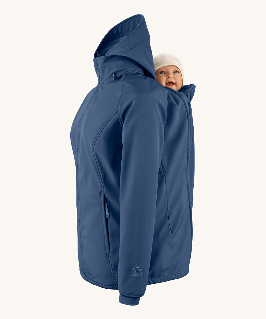 Mamalila soft shell baby wearing allrounder fitted jacket in navy available at Babipur showing a baby doll sitting on the back with the protective hood down