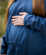 A close up of a mother wearing the Mamalila soft shell baby wearing allrounder fitted jacket in navy available at Babipur showing the insert attached to the front of the jacket