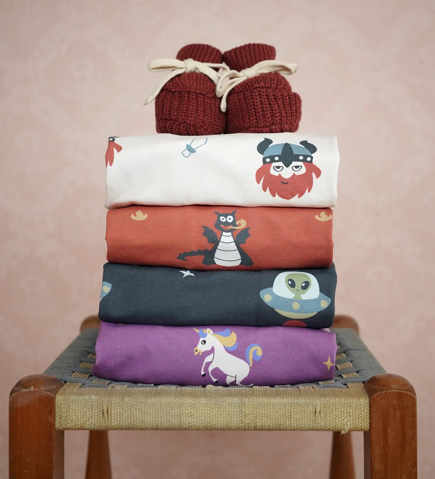Stack of Maxomorra kids long sleeve tops with Little Green Radicals knitted booties on top.