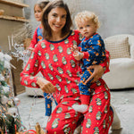 A woman wearing a Maxomorra Swedish Santa Adult Long Sleeve Pyjama Set holding a small child that is wearing a reindeer print rompersuit. 