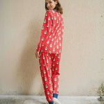 A woman wearing a Maxomorra Swedish Santa Adult Long Sleeve Pyjama Set standing in front of a beige coloured wall. The woman is facing away from the camera showing teh back of the pyjamas. 