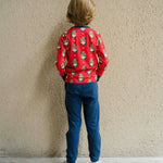 A child wearing a Maxomorra Swedish Santa Long Sleeve top, facing away from the camera showing the back of the top. The child is stood in front of a beige coloured wall.