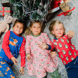 Three children lying on the floor looking up at the camera wearing clothing from the Maxomorra Christmas collection. 