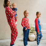 An adult and three children all wearing items from the Maxcomorra Christmas collection. The adult is wearing the Swedish Santa pyjamas, holding a baby wearing the reindeer print rompersuit. One of the other two children is wearing a Swedish Santa top and the last child is wearing a reindeer raglan top with reindeer print leggings. 