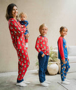 An adult and three children all wearing items from the Maxcomorra Christmas collection. The adult is wearing the Swedish Santa pyjamas, holding a baby wearing the reindeer print rompersuit. One of the other two children is wearing a Swedish Santa top and the last child is wearing a reindeer raglan top with reindeer print leggings. 