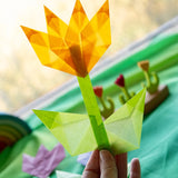 Adult hand holding a yellow flower made from Kite waxed paper