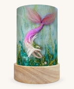 The Mermaid Treasures illustration by Het Wol Feetje sat in a Toverlux Magic Lantern base, on a cream background
