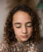 A child wearing the Namaki Natural Eyeshadow in Fawn colours. The colours on the child's eyelids are green, pink and gold
