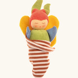 Nanchen soft butterfly doll in a brown striped blanket. Features a green body, blue arms, yellow wings and a red hat.