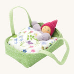 Nanchen Flower Bed doll with Carry Cot Toy, in green. A sweet little Waldorf doll which has been hand crafted in a terry material, is resting in a green and white spotted carry cot, under a beautiful botanical themed blanket. On a cream background