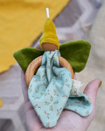 Nanchen flower fairy grasping toy made from organic cotton, each with a wooden ring, green velour wings, a yellow pointed hat, and a hanging loop, available at Babipur.