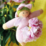 The Nanchen Flower Fairy Rattle Doll - Pink is sat on a beautiful pink rose