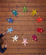 The Nanchen Waldorf Pimpel dolls in a circle, with a child playing with a light blue on in the bottom left hand corner
