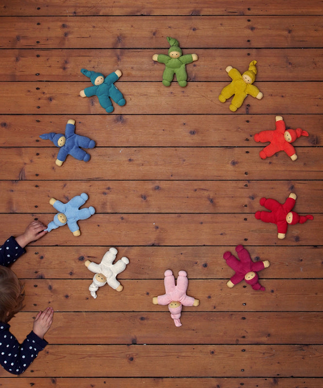 The Nanchen Waldorf Pimpel dolls in a circle, with a child playing with a light blue on in the bottom left hand corner