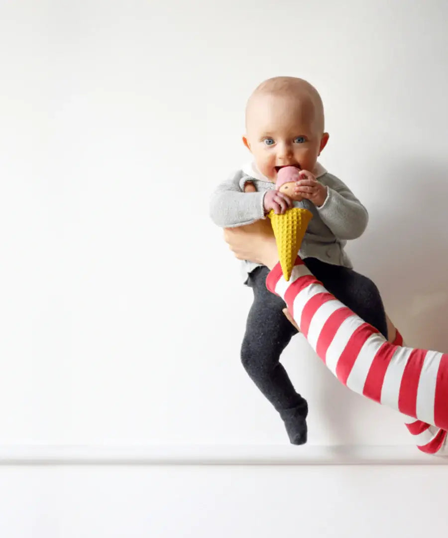 Adult holding a baby that's playing with the Nanchen ice cream rattle doll 