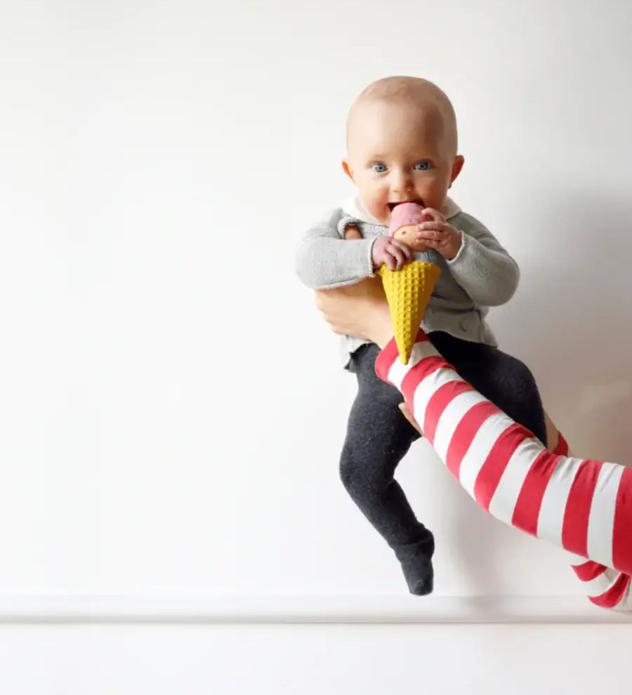 Adult holding a baby that's playing with the Nanchen ice cream rattle doll 