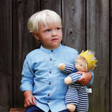 Child playing with Nanchen King Charles waldorf cuddle doll on a wooden bench doll has a blue and white outfit, yellow crown and blue scarf