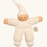 Nanchel pimpel waldorf doll in cream white. Showing cute facial features and a tie on the hat. Doll has a terry cloth body 
