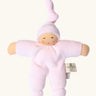 Nanchel pimpel waldorf doll in pastel pink. Showing cute facial features and a tie on the hat. Doll has a terry cloth body 