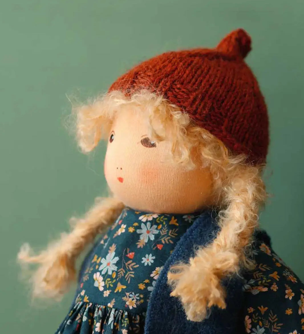 Nanchen winterchild lotta doll showing close up of the Waldorf style face and knitted orange hat