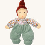 Nanchen Forest Child Waldorf Doll - Sage. This beautifully handcrafted doll wears sage velour trousers, a brown hat and a floral top. On a cream background