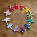 A collection of Hand crafted Nanchen Pimpel Dolls, arranged in a circle on wooden flooring. The colours resemble the rainbow