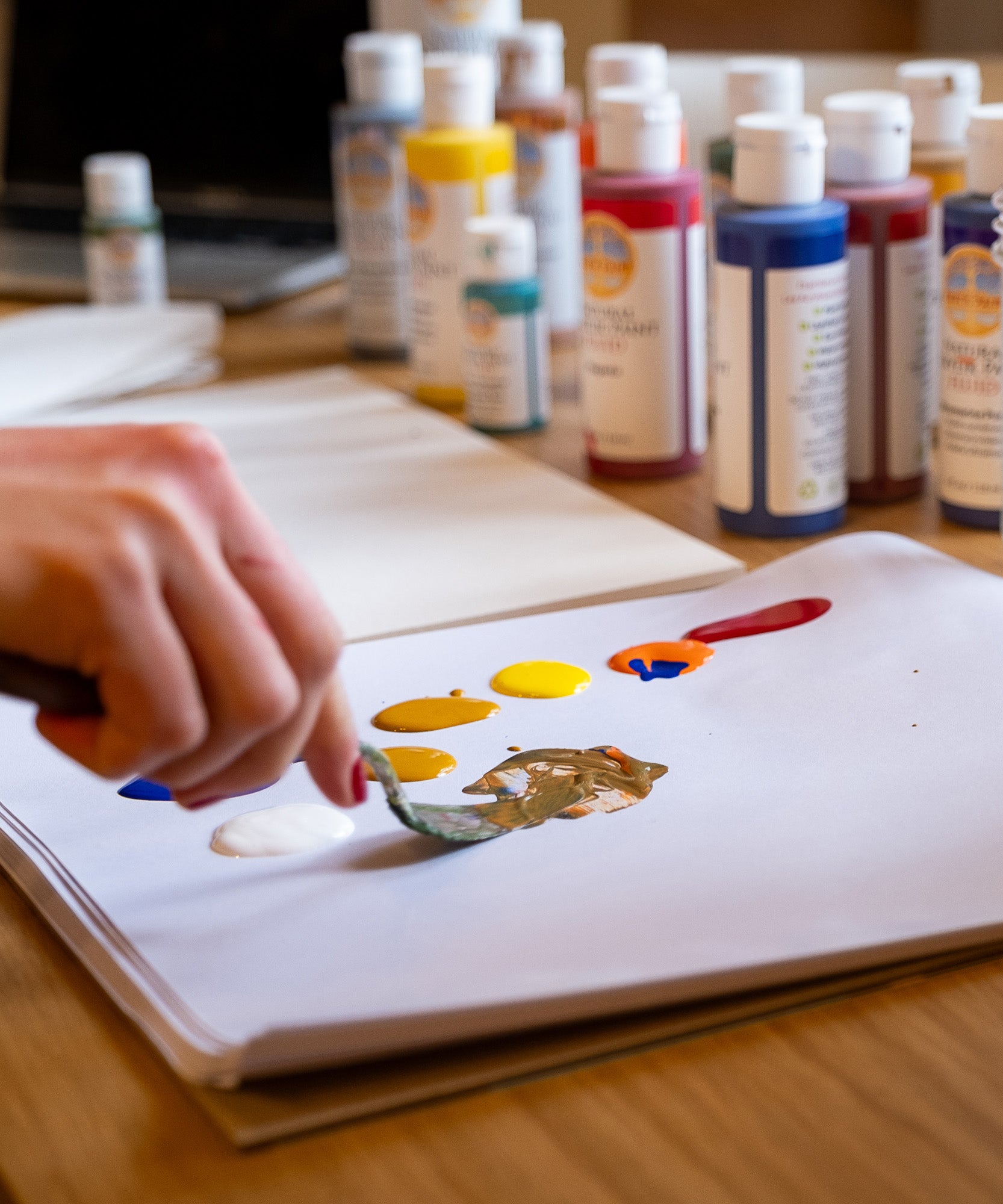 A close up of an artist holding a palette knife using the Natural Earth Paint acrylic paints on paper