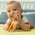 A child using Fanfan The Fawn as a teether whilst laying down. The child is happy and smiling whilst playing with the Fanfan The Fawn Natural Rubber Teething Toy