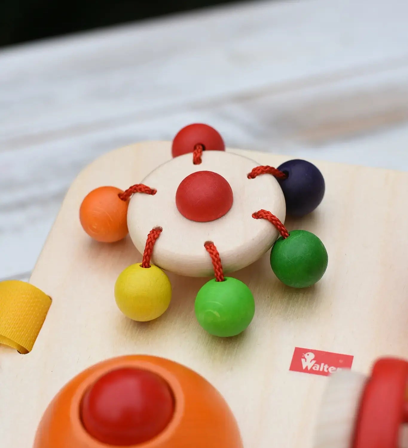 Close up of the carouserl rattle top attached to the Nic Wooden Baby Game busy Board with 4 four activities.