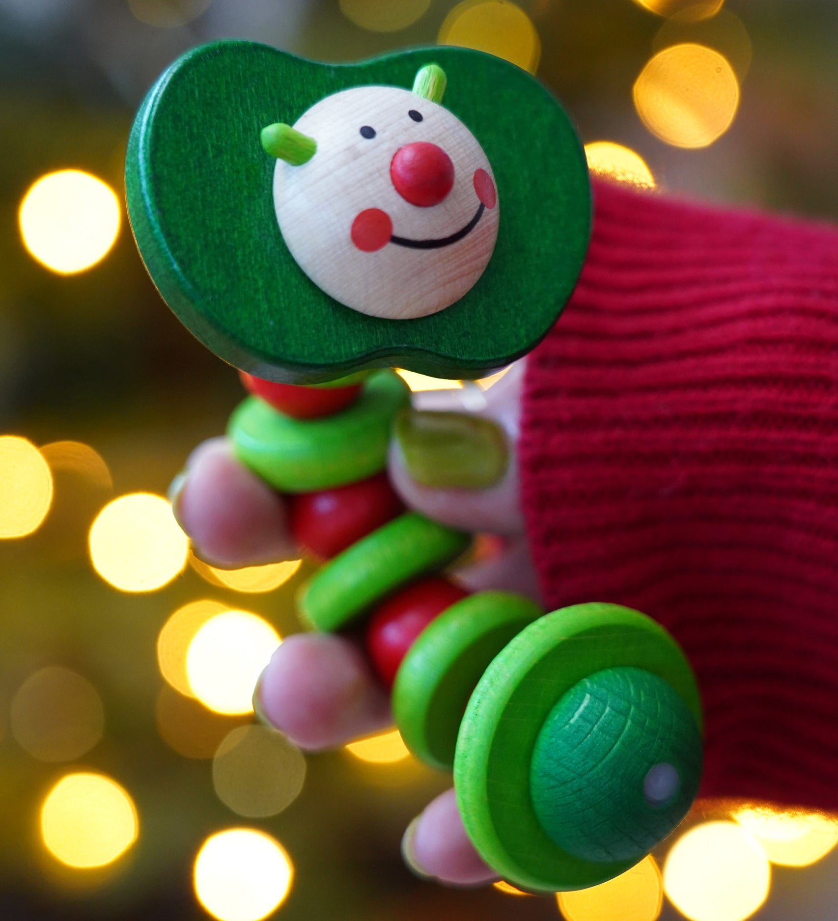 Baby wooden grasping toy, Nic Apple Worm, a smiling worm on a flexible rope lined with chunky red and green beads, for sale at Babipur. 