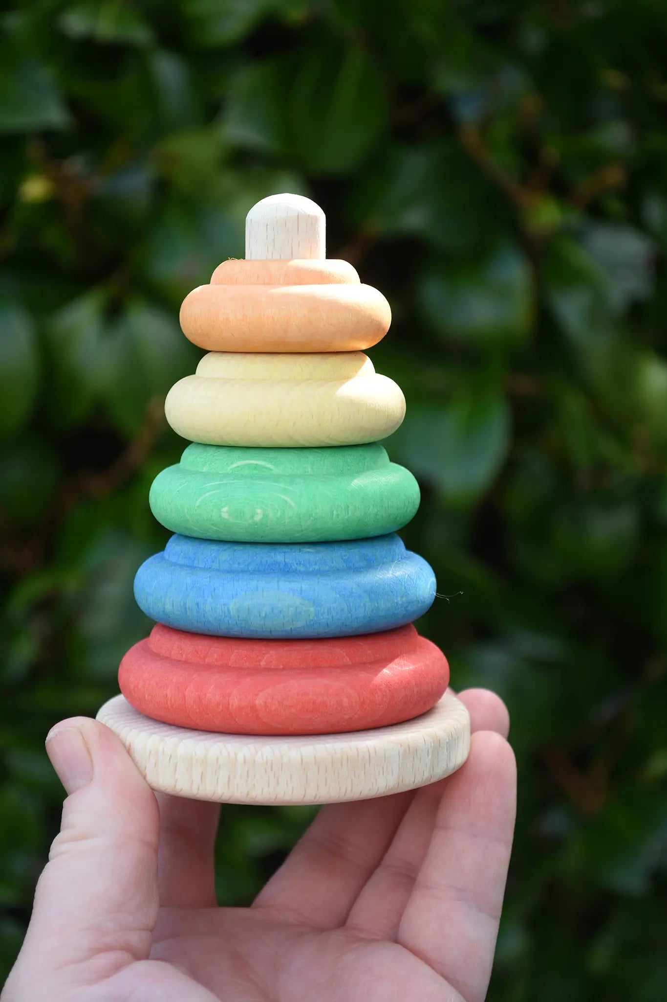 Nic Classic Stacking Tower wooden baby toy in an adult's hand.