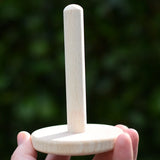 Wooden pole from the Nic Classic Stacking Tower placed on a wooden board in an adult's hand.
