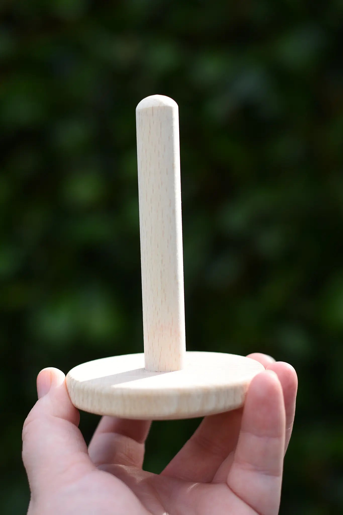 Wooden pole from the Nic Classic Stacking Tower placed on a wooden board in an adult's hand.