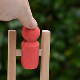 Close up of the Nic climbing wooden ladder toy with a small red peg person being placed on the top ring.