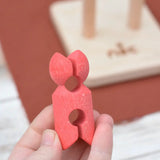 Red peg doll figure from the Nic climbing wooden ladder toy in a adult's hand.