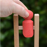 Hand placing the red peg doll onto the top of the ladder of the Nic climbing wooden ladder toy.