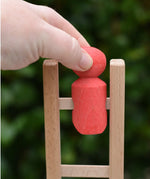 Hand placing the red peg doll onto the top of the ladder of the Nic climbing wooden ladder toy.