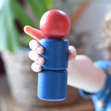 A child's hand holding a wooden toy peg dolls style figure with a red round head and blue stacked body parts, created using parts from the Nic screws and nuts colorful wooden toy threaded blocks and shapes set.