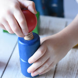 Close-up of a child's hands playing with a blue wooden toy block featuring a red spherical top from the Nic screws and nuts colorful wooden toy threaded blocks and shapes set.