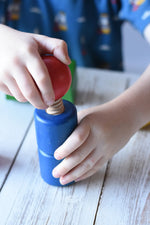 Close-up of a child's hands playing with a blue wooden toy block featuring a red spherical top from the Nic screws and nuts colorful wooden toy threaded blocks and shapes set.