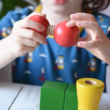 Child threading the two red wooden toy balls one with a thread connector from the Nic screws and nuts colorful wooden toy threaded blocks and shapes.
