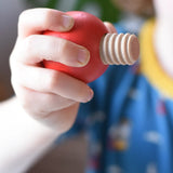 Close-up of a child's hand holding a red, ball-shaped wooden screw from the Nic screws and nuts colorful wooden toy threaded blocks and shapes set.