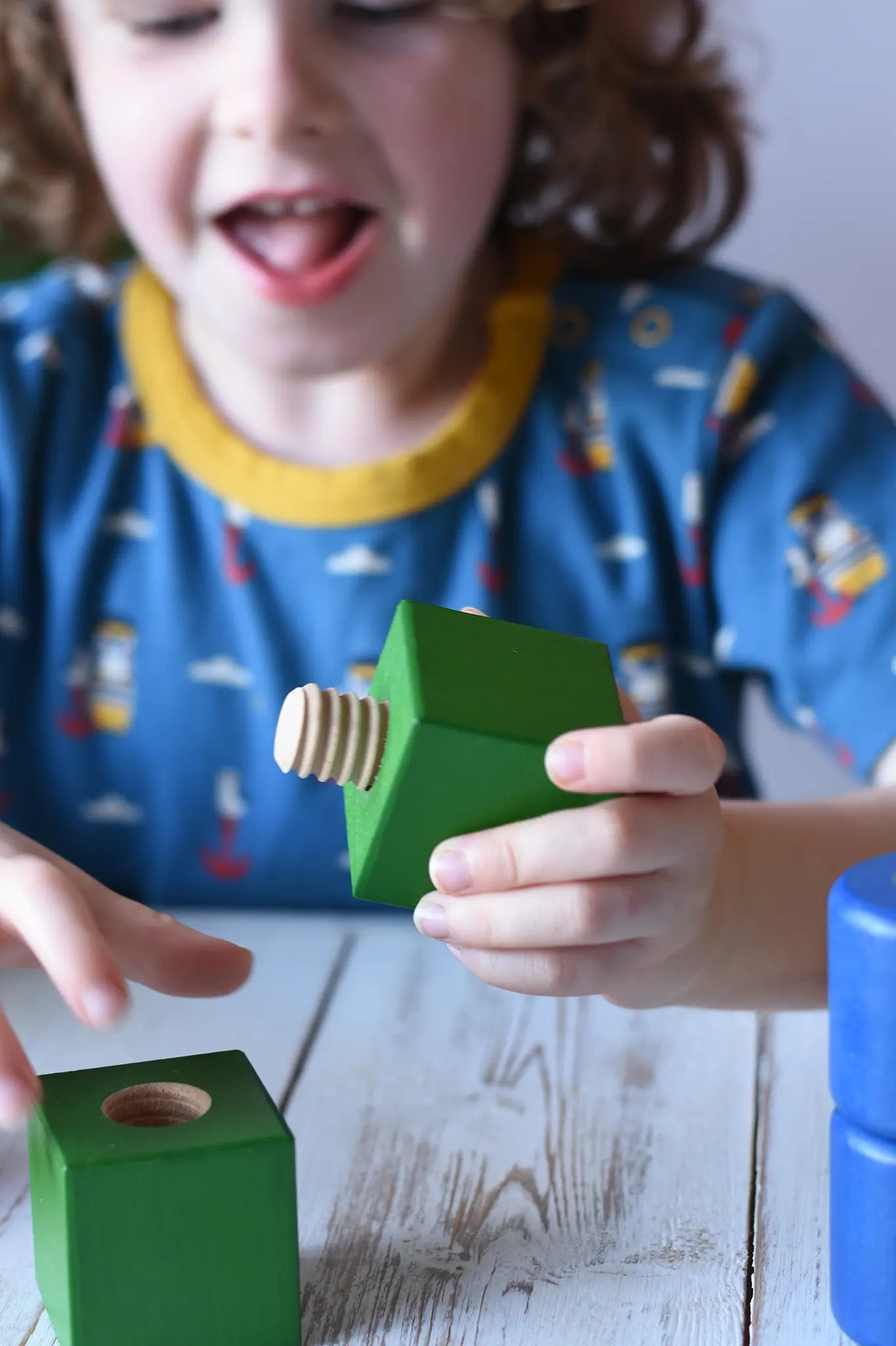 Child playing with pieces from the Nic screws and nuts colorful wooden toy threaded blocks and shapes set.